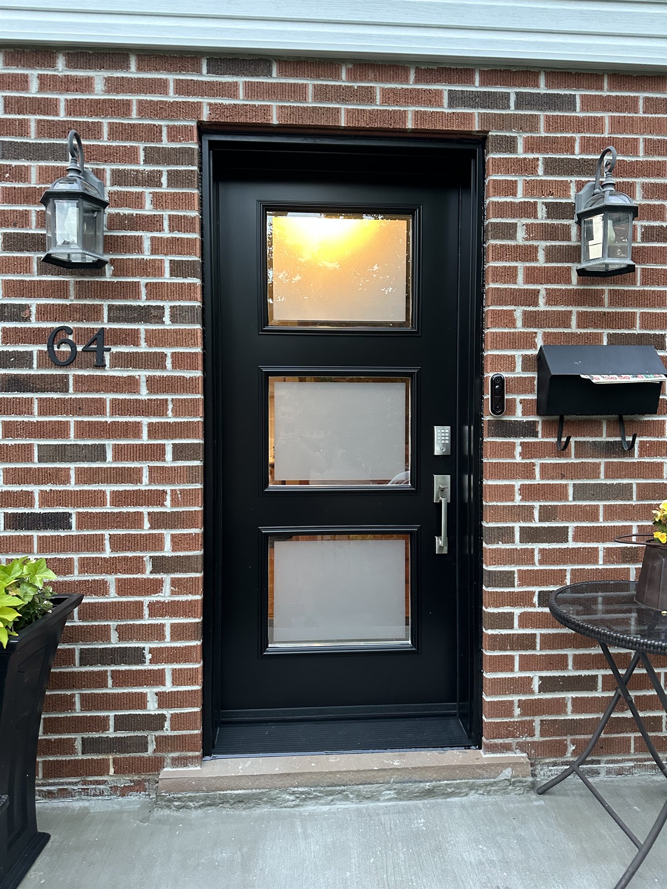 Black entry door with three rectangular glass lites in the same red brick opening