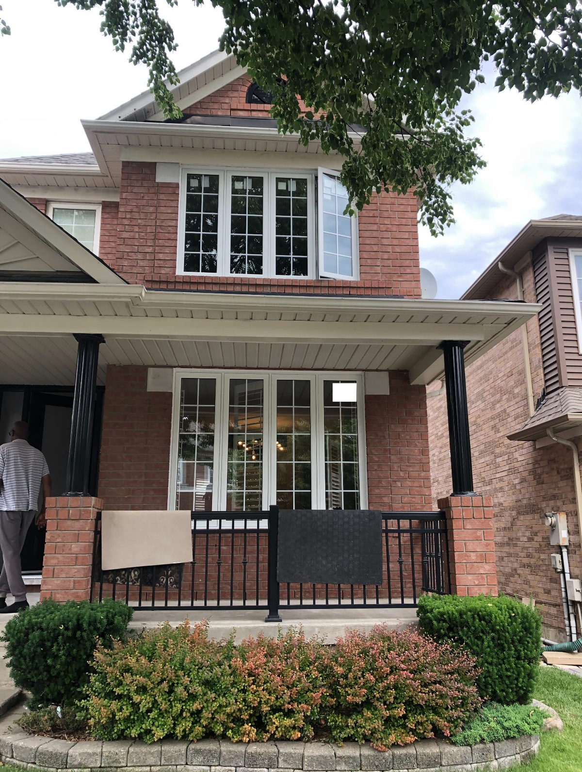 Red brick house with two white-framed bay window groupings with colonial grid grills, one casement open outward