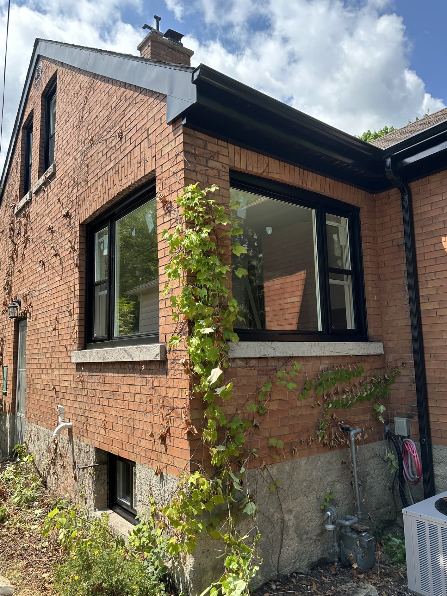 Same brick corner with large black-framed windows and a black basement window